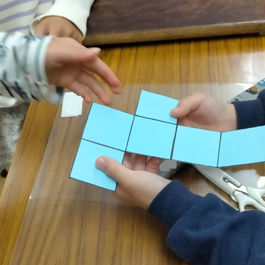 立方体を展開してみる小学生たち（工作の教室での様子1）
